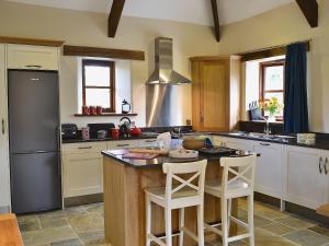 a kitchen with a island with two white bar stools at Jacks Barn - Hssu in Welcombe