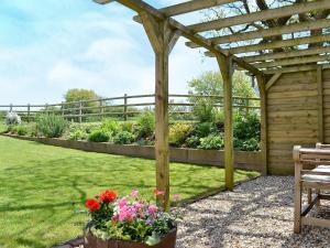 a wooden pergola with flowers in a garden at Jacks Barn - Hssu in Welcombe