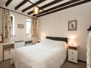 1 Schlafzimmer mit einem weißen Bett, 2 Tischen und 2 Fenstern in der Unterkunft Sky Lark in Weybourne