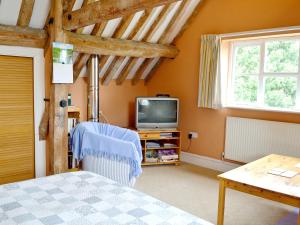 a bedroom with a bed and a tv and a table at The Stable-e2836 in Whitminster