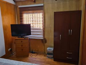 1 dormitorio con TV en un tocador y una ventana en Cabañas Arlenne, en Valdivia