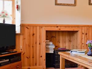 Habitación con tabique de madera, TV y mesa. en Rams Cottage en Glenelg
