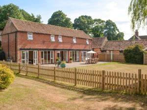 an old brick house with a wooden fence at Fiddledrill Barn in Benniworth