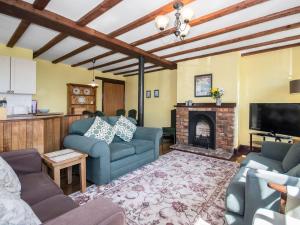 a living room with blue couches and a fireplace at Lavender Cottage II in Scalby