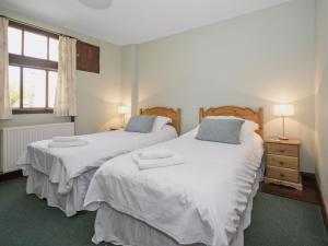 two beds in a bedroom with two lamps and a window at Lavender Cottage II in Scalby