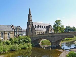 a bridge over a river in front of a church at Morpeth Court in Morpeth