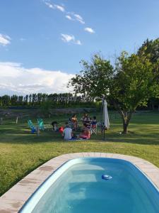 un groupe de personnes assises dans l'herbe près d'une piscine dans l'établissement Casa de Campo La Magdalena, à Tunuyán