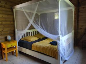 1 dormitorio con cama con dosel y mesa en LE TRI HAUT DE BELLEVUE - Bungalow Colibri, en Pointe-Noire