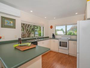 a kitchen with white cabinets and a green counter top at Beach Beauty - Pauanui Holiday Home in Pauanui