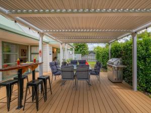 a wooden deck with a pergola and a grill at Beach Beauty - Pauanui Holiday Home in Pauanui