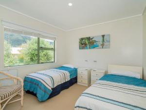 two beds in a white room with a window at Beach Beauty - Pauanui Holiday Home in Pauanui