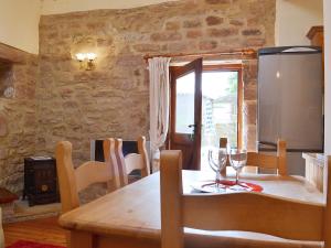 a dining room with a wooden table with wine glasses at Barn Owl Cottage in Cromford