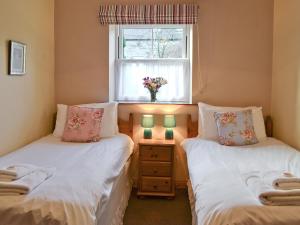 two twin beds in a room with a window at Manor Farm Cottage in Carperby