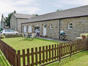 a stone house with a fence in front of it at Manor Farm Cottage in Carperby