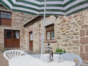 a table with a green and white umbrella and chairs at Barn Owl Cottage in Cromford