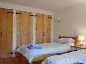 two beds in a bedroom with wooden cabinets at Barn Owl Cottage in Cromford