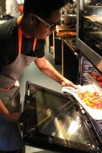 a man putting a pizza into an oven at Hotel Andra Seattle MGallery Hotel Collection in Seattle