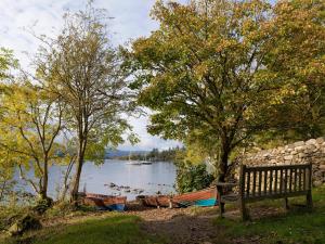 a bench sitting next to a lake with boats at West View in Bowness-on-Windermere