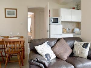 a living room with a leather couch and a kitchen at West View in Bowness-on-Windermere