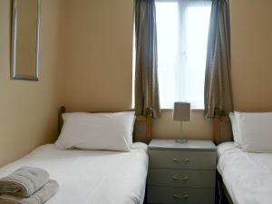 two twin beds in a room with a window at West View in Bowness-on-Windermere