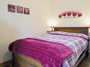 een slaapkamer met een bed met een paarse deken bij Dairy Cottage - E5279 in Shincliffe