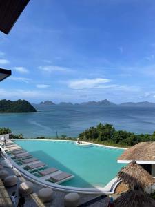 a swimming pool with lounge chairs and the ocean at El Nido Bayview Resort in El Nido