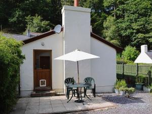 einen Tisch und Stühle mit einem Regenschirm vor einem Haus in der Unterkunft Minafon in Penmaen-mawr