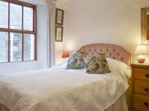 a bedroom with a white bed with pillows and a window at Begbie Cottage in Bowness-on-Windermere