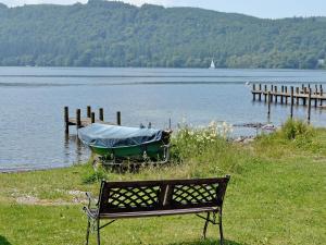 a bench sitting next to a boat on a lake at Begbie Cottage in Bowness-on-Windermere