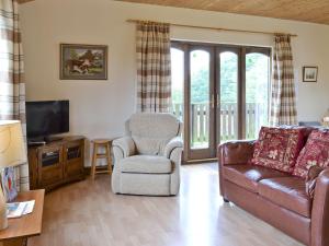 sala de estar con sofá, silla y TV en Woodside Lodge - Hw7520 en Penybont