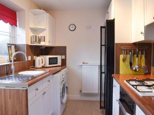 een keuken met witte kasten en een zwarte koelkast bij Glendalough in Hunmanby