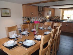 a wooden table with plates and wine glasses on it at Gateside Farmhouse Sedbergh in Sedbergh