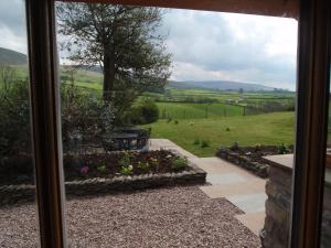 a view from a window of a garden with a table at Gateside Farmhouse Sedbergh in Sedbergh