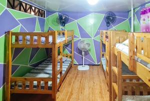 a room with three bunk beds and a wall with a mural at Yuzon Bedspace Transient Home & Staycation in Manila