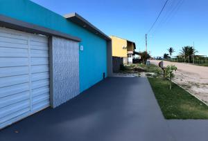 プラドにあるCasa com piscina e um quarto com ar split pé na areia a 50 metros da praiaの青い建物と歩道のあるガレージ