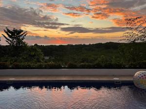 a swimming pool with a sunset in the background at Puesta del Sol in Quepos