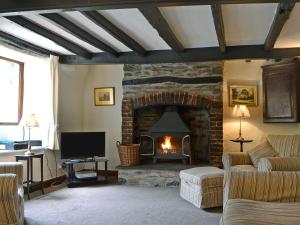 a living room with a fireplace with a couch and a tv at 1 Oaks Farm Cottages in Ambleside