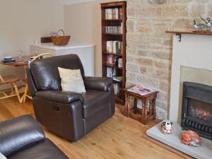 a living room with a leather chair and a fireplace at The Old Vicarage in Curbar