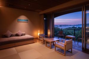 a room with a bed and a balcony with a view at KAMENOI HOTEL Toba in Toba