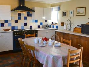 uma cozinha com uma mesa com cadeiras e um fogão em Seafarers em Lessingham