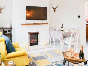 sala de estar con chimenea y TV en la pared en Wellwood Cottage, en Morpeth