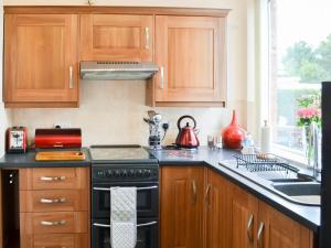 a kitchen with wooden cabinets and a stove top oven at Wellwood Cottage in Morpeth