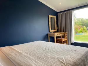 a blue bedroom with a bed and a desk at Phan Thiet BeachHouse in Phan Thiet