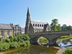 un puente sobre un río frente a una iglesia en Wellwood Cottage en Morpeth