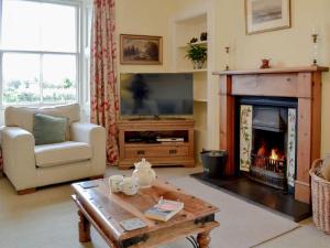 a living room with a fireplace and a tv at Islabank Farmhouse - Saap in Kirkton of Airlie