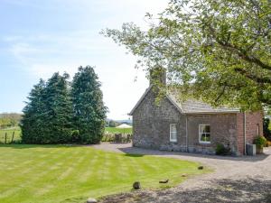 a stone house with a lawn and trees at Islabank Farmhouse - Saap in Kirkton of Airlie