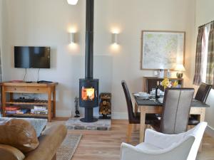 a living room with a wood stove and a table at Fig Cottage in Brabourne