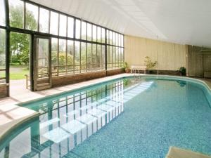 a large swimming pool in a building with windows at Old Hall Farm House in Saint James