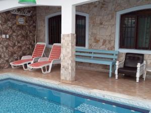 a villa with a swimming pool and a house at Maranata Casa com Piscina - 2 minutos de carro até o mar in Peruíbe