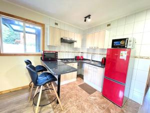 a kitchen with a red refrigerator and a table and chairs at Cabañas y Deptos Cuatro Estaciones in Frutillar